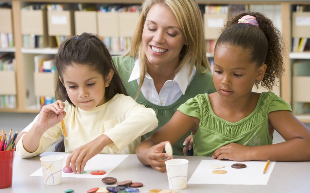 Kindergarten teacher sitting with students and smiling in art class